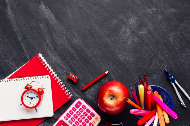 Rifornimenti di scuola rosso brillante e apple sulla lavagna