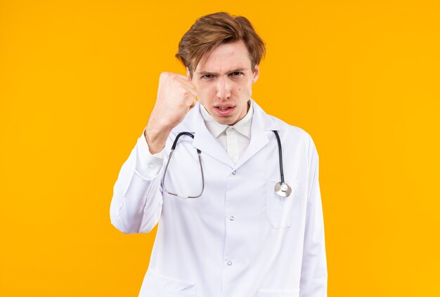 Rigoroso giovane medico maschio che indossa una tunica medica con uno stetoscopio che tiene il pugno