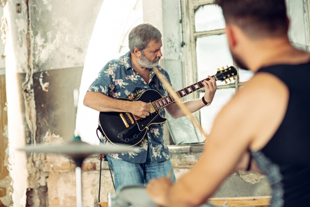 Ripetizione della band di musica rock. Chitarrista elettrico e batterista dietro la batteria.