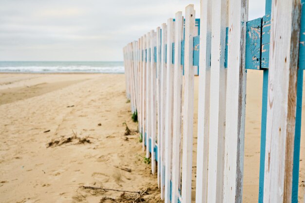 Riposo fuori stagione. Spiaggia di primavera deserta, recinzione di fronte a una spiaggia pubblica, cielo nuvoloso in attesa di pioggia. Spiaggia di mare fuori stagione, luogo per il testo