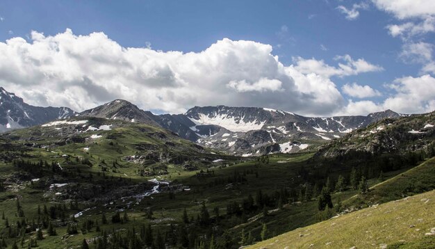 Ripresa a tutto campo di una catena montuosa con alberi intorno e uno spesso strato di nuvole nel cielo