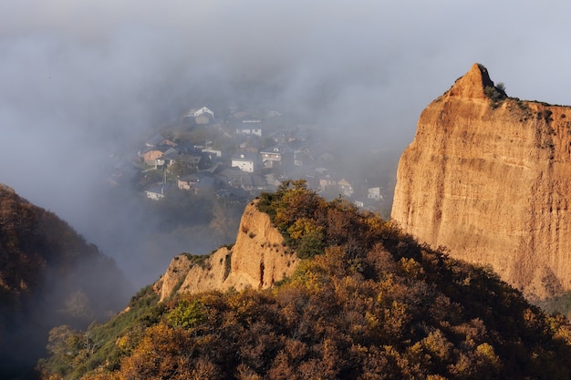 Ripresa ad alto angolo di una montagna coperta di alberi con un villaggio catturato nella nebbia