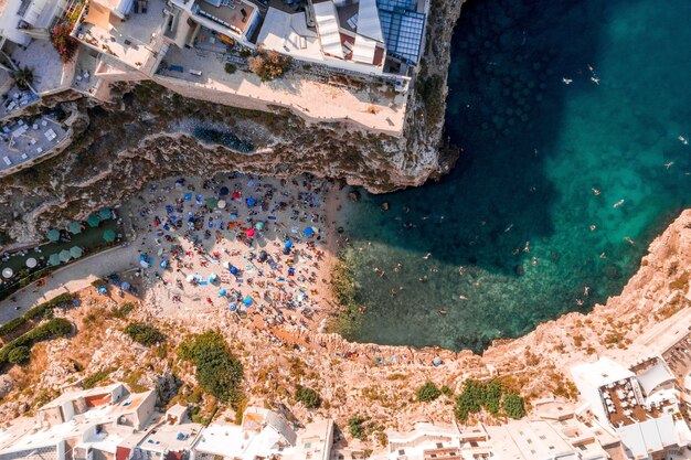 Ripresa aerea di persone che nuotano nel mare Adriatico circondate da scogliere sotto la luce del sole