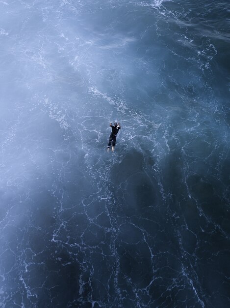 Ripresa aerea di un bellissimo paesaggio marino e una persona che nuota nel mare sotto la luce del sole