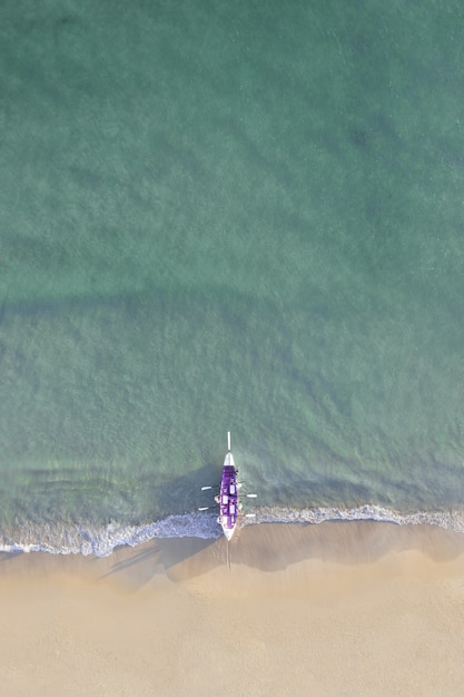 Ripresa aerea di una barca viola su una bellissima spiaggia sotto la luce del sole
