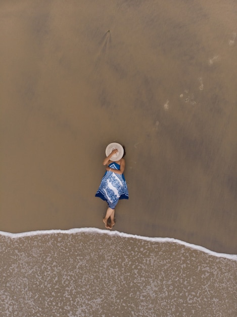 Ripresa aerea di una donna asiatica sdraiata su una spiaggia sabbiosa