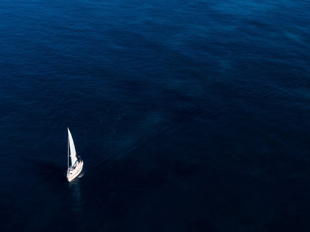 Ripresa aerea di una piccola barca bianca a vela nell'oceano