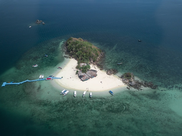 Ripresa aerea di una piccola isola con pochi edifici e barche e un molo blu