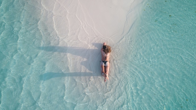 Ripresa aerea di una ragazza in posa sulla sabbia e abbronzatura in spiaggia