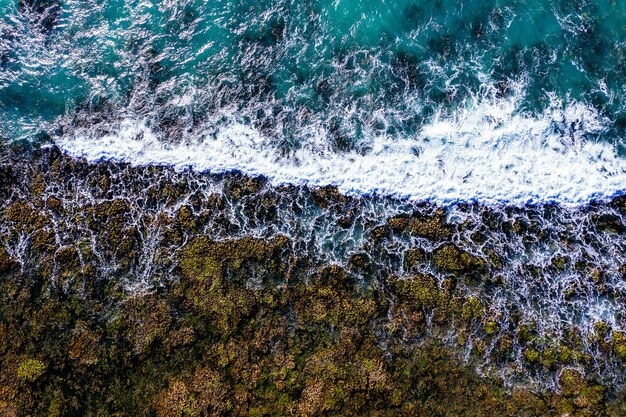 Ripresa aerea di una spiaggia rocciosa con onde spumose