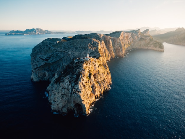 Ripresa aerea distante di un'alta scogliera rocciosa con una torre bianca costruita in cima all'oceano