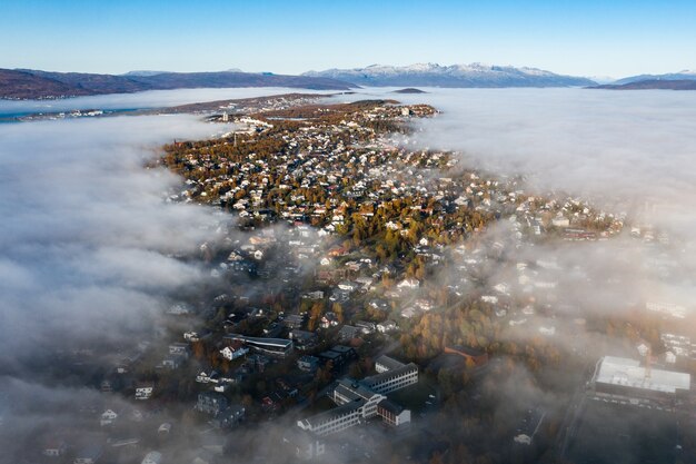 Ripresa aerea mozzafiato del paesaggio urbano circondato da alberi verdi sotto un cielo nuvoloso panoramico