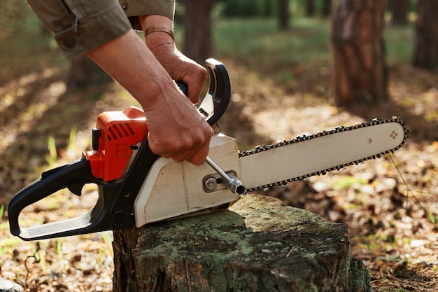 Ripresa all'aperto di un lavoratore sconosciuto che ripara la motosega prima o dopo la deforestazione