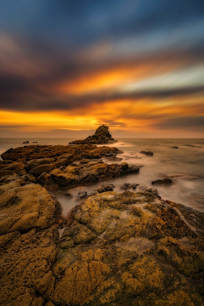 Ripresa verticale delle pietre in riva al mare sotto la fantastica alba