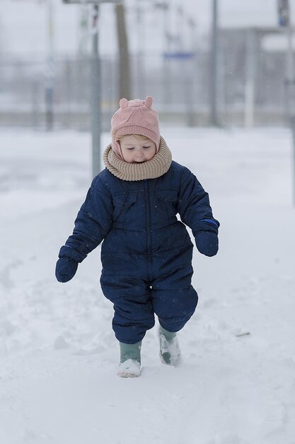 Ripresa verticale di un bambino che corre felice nella neve in una fredda giornata invernale