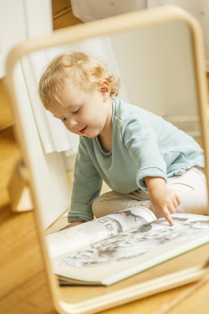 Ripresa verticale di un bambino che legge un libro di fiabe visibile allo specchio