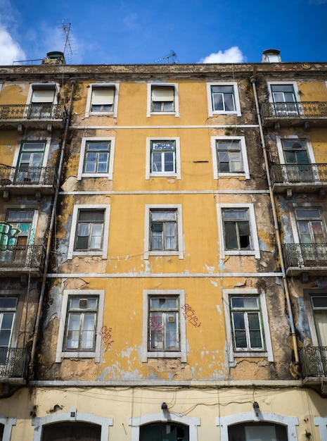 Ripresa verticale di un vecchio condominio dipinto di giallo con alcune finestre rotte