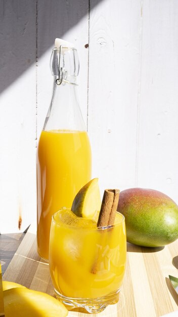 Ripresa verticale di una bevanda rinfrescante al mango con un bastoncino di cannella su una superficie di legno