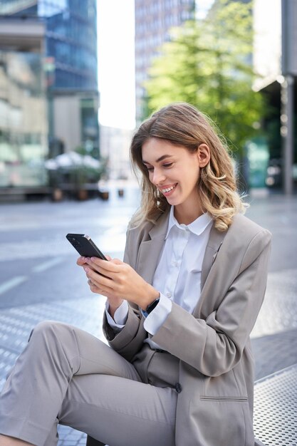 Ripresa verticale di una donna d'affari sorridente che guarda l'app per smartphone che invia un messaggio sull'ode del telefono cellulare