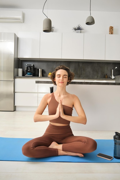 Ripresa verticale di una giovane donna che medita facendo yoga a casa su un tappetino di gomma a casa