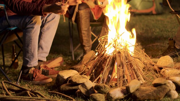 Riprese a mano di un uomo che fa fuoco da campo per i suoi amici in una notte fredda.