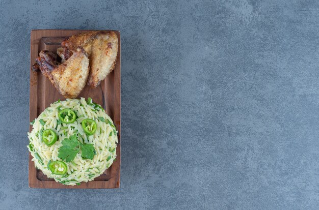 Riso al vapore con parti di pollo su tavola di legno.