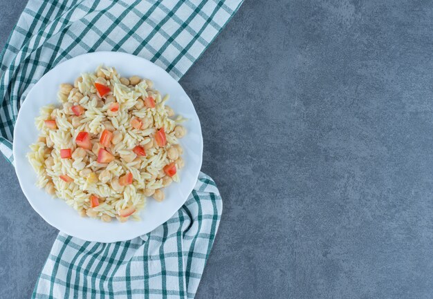 Riso al vapore con piselli e fette di pomodoro su piastra bianca.