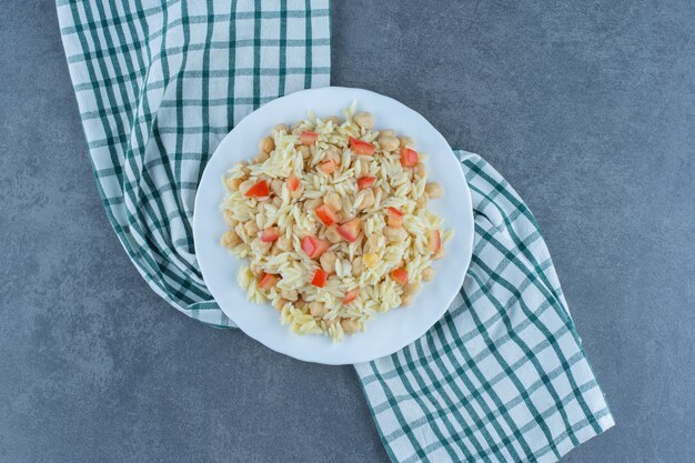 Riso al vapore con piselli e fette di pomodoro su piastra bianca.