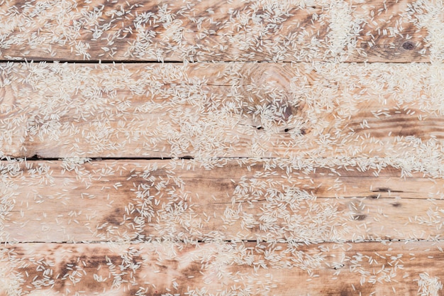 Riso bianco crudo sparsi sulla superficie in legno con texture