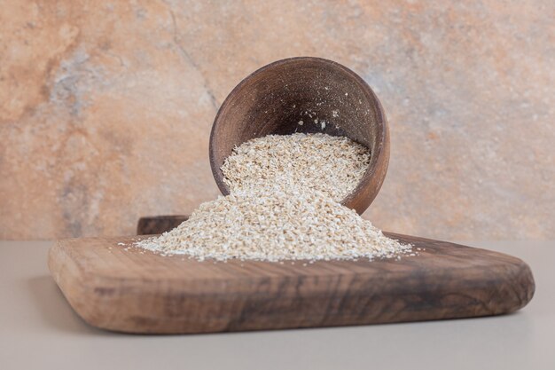 Riso bianco in una tazza di legno su un piatto di legno.