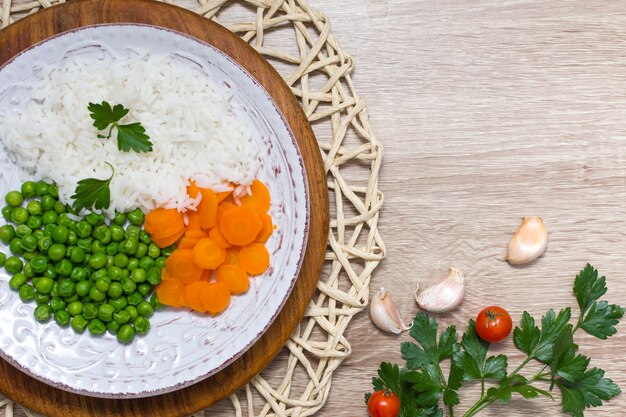 Riso cotto con verdure e prezzemolo sul piatto sulla tavola di legno