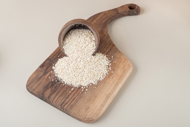 Riso in una tazza di legno su un piatto di legno.