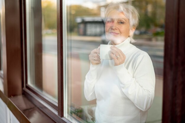 Rispecchiare il caffè bevente femminile senior