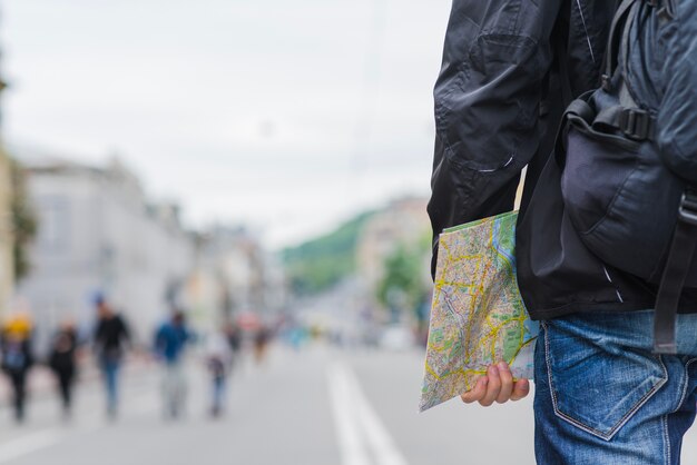 Ritaglia l&#39;uomo con la mappa sulla strada della città