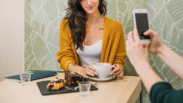 Ritaglia la donna che posa per la foto in caffè