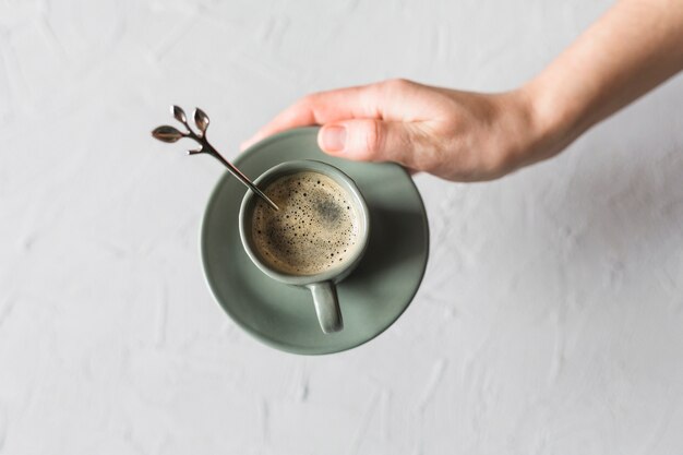 Ritaglia la mano con una tazza di caffè e un piattino