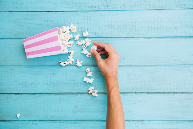 Ritaglia la mano prendendo popcorn dalla scatola di popcorn