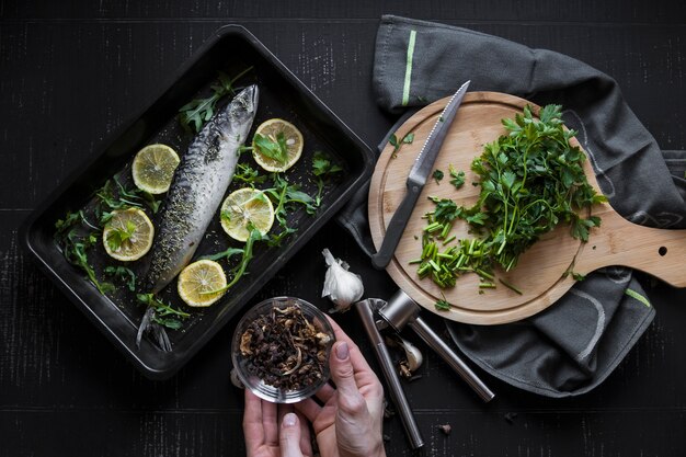 Ritaglia le mani che tengono le spezie vicino al pesce