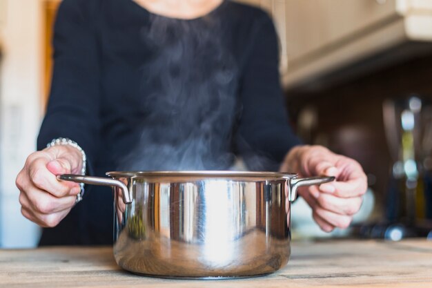 Ritaglia le mani della donna che cucina il piatto in cucina