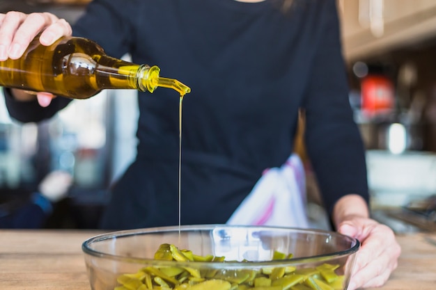 Ritaglia le mani della donna che cucina insalata in cucina