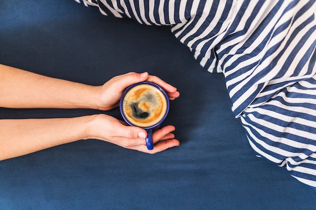 Ritaglia le mani tenendo la tazza con il caffè