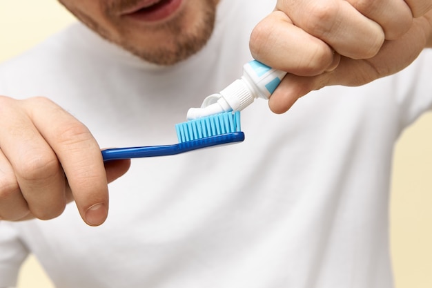 Ritagliata colpo di uomini che usano pasta per dente.