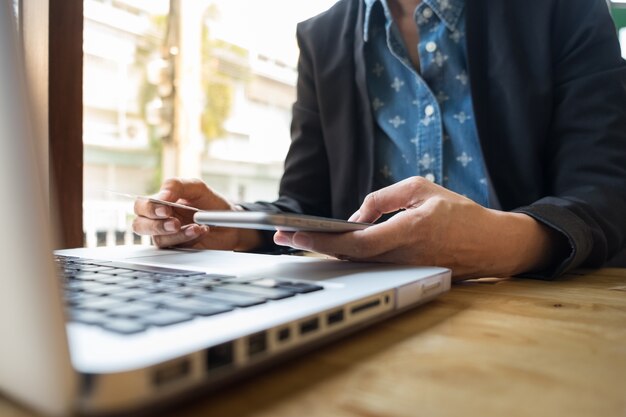 Ritagliata immagine di donna che inserisce le informazioni sulla carta e chiave sul telefono o laptop mentre acquisti online.