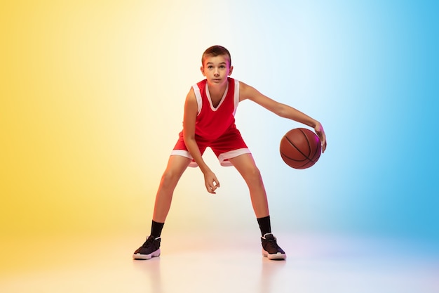 Ritratto a figura intera di giovane giocatore di basket in uniforme su parete sfumata