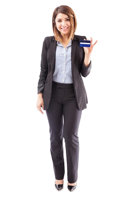 Ritratto a figura intera di una bella rappresentante di banca femminile che tiene una carta di credito e invita i clienti a richiederla