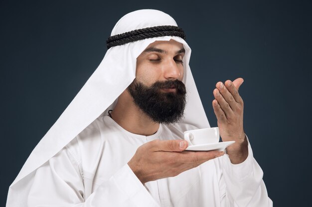 Ritratto a mezzo busto dell'uomo d'affari arabo saudita su studio blu scuro