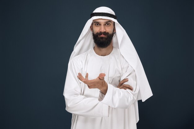 Ritratto a mezzo busto dell'uomo d'affari arabo saudita sulla parete blu scuro dello studio