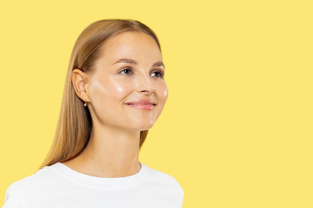 Ritratto a mezzo busto della giovane donna caucasica su sfondo giallo studio. Bello modello femminile in camicia bianca