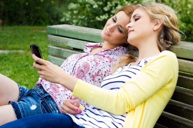 Ritratto all&#39;aperto di due belle giovani donne con mobili al parco