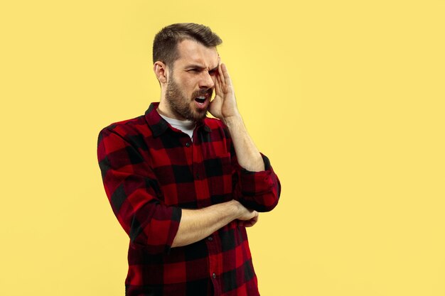 Ritratto alto vicino a mezzo busto di giovane uomo in camicia su giallo